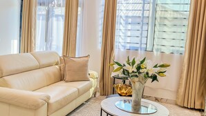 En moderne stue med en beige sofa, et glasbord og en dekorativ vase med blomster.