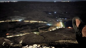 Een nachtzicht van een rotsachtig landschap met verlichte stadslichten in de verte.