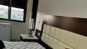 Een hotelkamer met een bed, nachtkastje, lamp en raam.