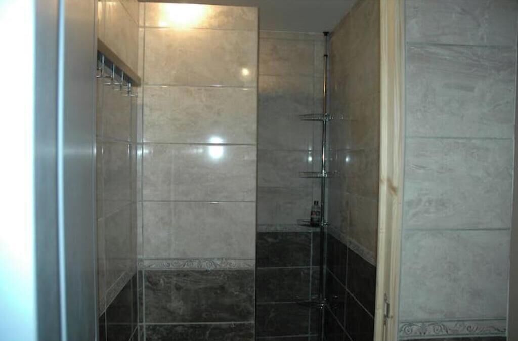 Een badkamer met betegelde wanden en een douchecabine met glazen wanden.