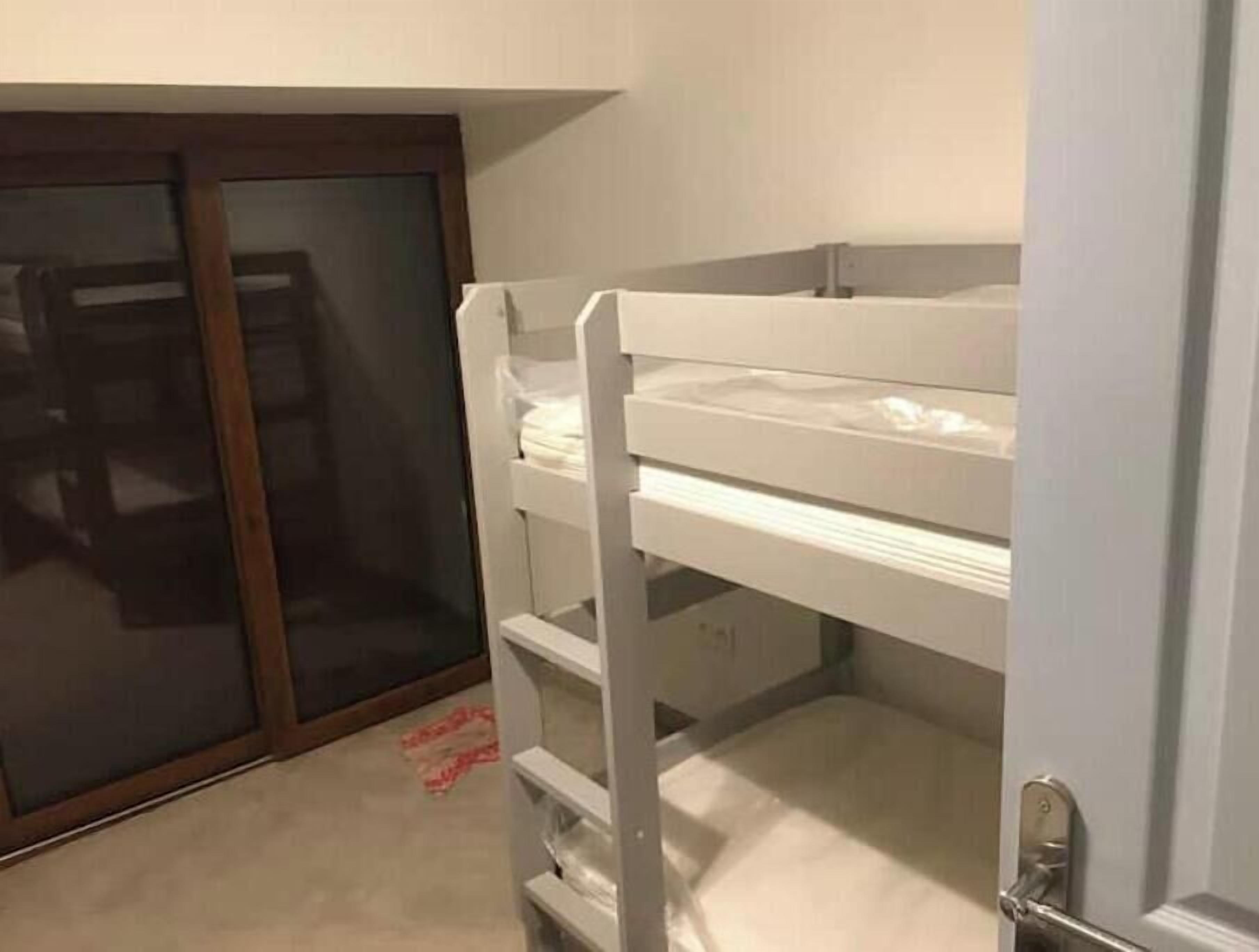Een stapelbed met een onderbed en een deur naar een inloopkast met glazen schuifdeuren.