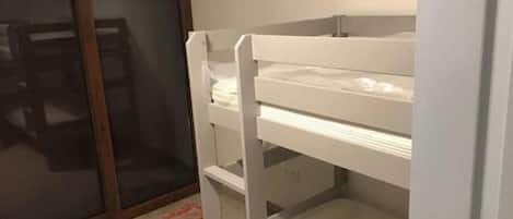 A bunk bed with a lower bunk and a door to a sliding glass door closet.