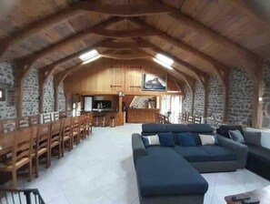 Un vaste espace de vie de style loft, doté d’un haut plafond, de murs en pierre, d’un grand canapé et d’un coin repas avec des chaises en bois.