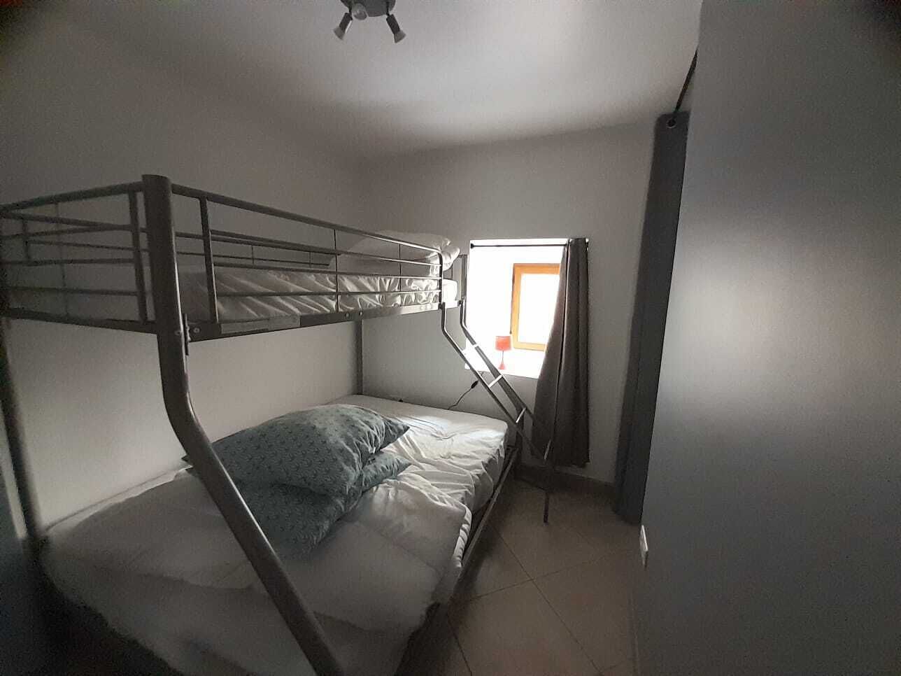 A bunk bed room with a window and a door.