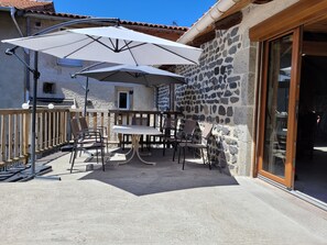 An outdoor patio with a table and chairs, a large umbrella, and a stone wall.