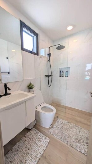 A modern bathroom with a shower, toilet, and sink. - Cana Life Luxury | City Beach Pool View Suite (Punta Cana)