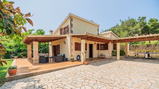 A two-story house with a patio area, outdoor furniture, and potted plants. - 2-bed Villa With Pool, Puerto Pollenca (Pollença)