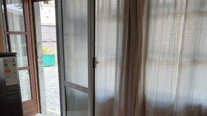 Ein Zimmer mit einer Schiebetür zum Außenbereich, einem Fliesenboden und einem Kühlschrank.