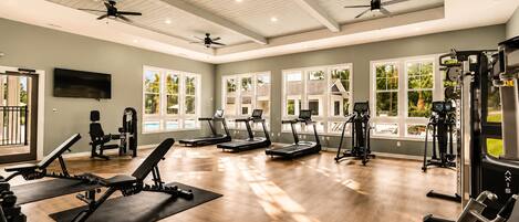A gym with treadmills, weight machines, and a ceiling fan.