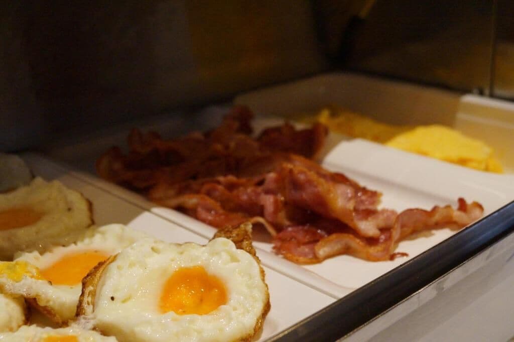 A breakfast buffet with scrambled eggs, bacon, and toast.