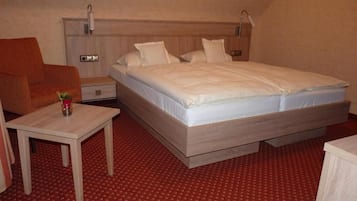 Ein Hotelzimmer mit einem Einzelbett, einem Nachttisch, einem kleinen Tisch und einem roten Teppichboden.