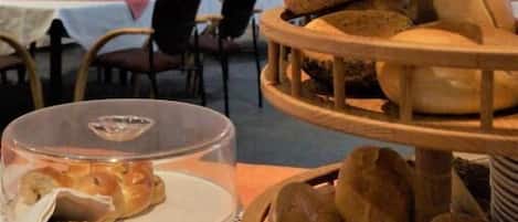 A multi-tiered wooden bread display in a dining area with tables and chairs in the background.
