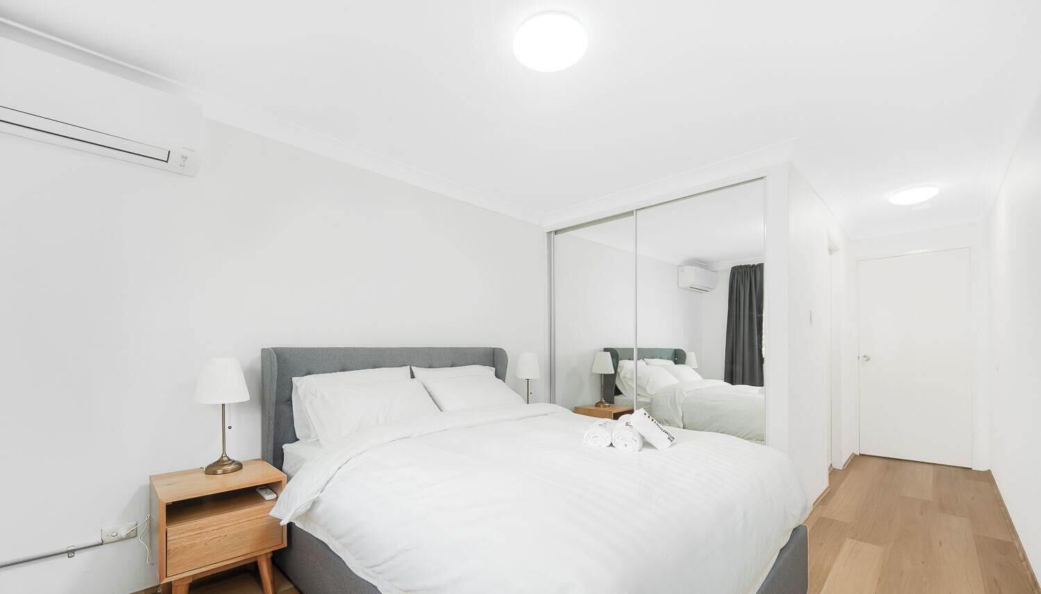 Une chambre d’hôtel moderne équipée d’un lit, de tables de chevet, d’un miroir et d’une armoire.