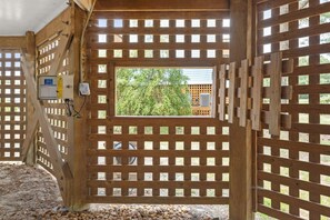 Ein Holztor mit Fenster, einem Verteilerkasten und Blick auf Grünfläche.