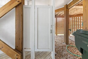 A wooden structure with a white door, a wooden floor, and a green hose. - Dolphin's Cove: Dog Friendly | Hot Tub (Corolla)