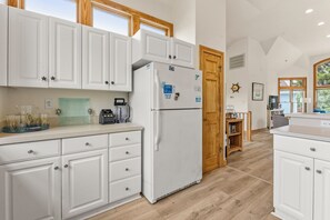 Eine moderne Küche mit weißen Schränken, einem integrierten Kühlschrank und einer Holztür.
