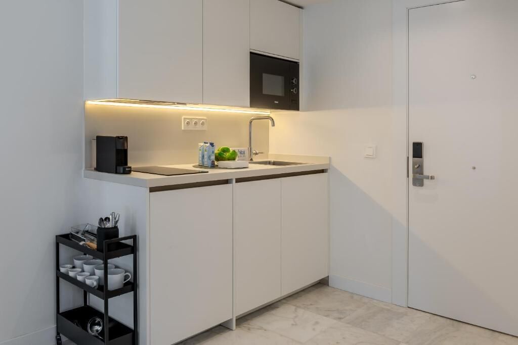 Una cucina moderna con mobili bianchi, forno a microonde integrato e una macchina per il caffè nera.