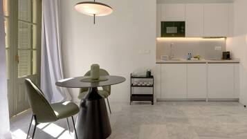 A modern kitchen with a microwave, a sink, and a small countertop. There is a dining area with a table and chairs.