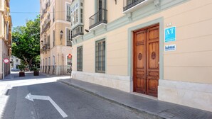Vista de la calle con un edificio que tiene una puerta de madera grande, un letrero que dice 'Habitat Apartments' y una señal de tráfico de 'prohibido el paso'.