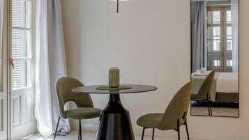 Habitación de hotel con una mesa redonda, dos sillas, un florero, un espejo y una cama.