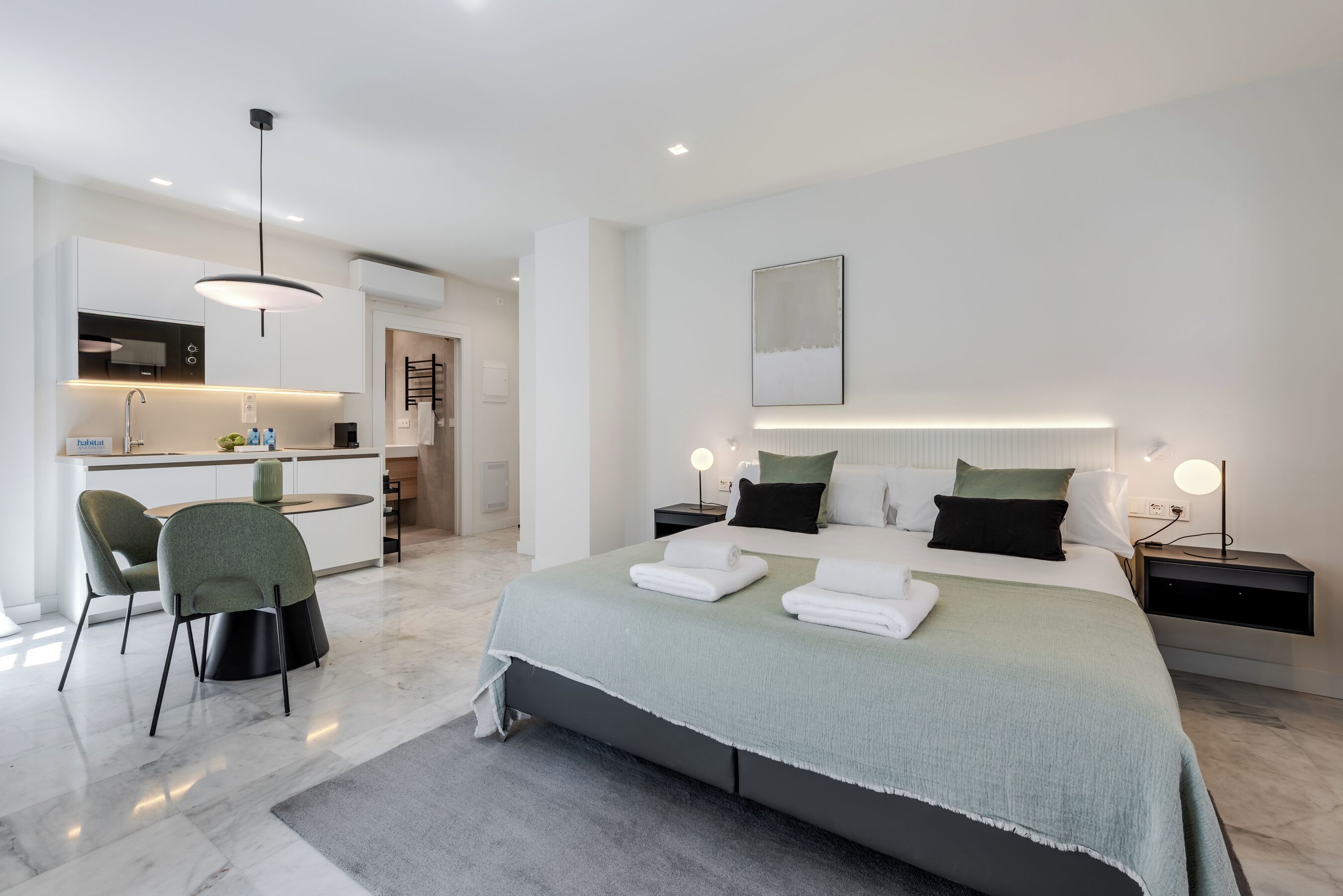 A modern hotel room with a bed, bedside tables, a desk, and a chair.