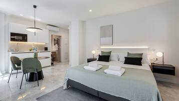 A modern hotel room with a bed, bedside tables, a desk, and a chair.