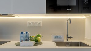 Una cocina moderna con microondas integrado, un lavamanos de acero inoxidable y un cartel de kit de limpieza.