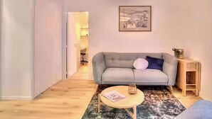 A living room with a sofa, a coffee table, and a lamp. - Celine 29 (Paris)