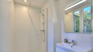 A modern bathroom with a glass-enclosed shower, a white sink, and a mirror above it. - Celine 29 (Paris)
