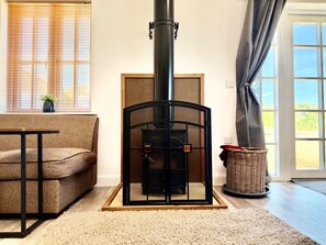 Une pièce chaleureuse avec un poêle à bois, un canapé, une table et un panier en osier.