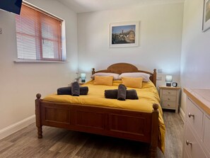 Un lit bien fait, avec une tête de lit en bois, une table de chevet avec une lampe et un tableau accroché au mur.