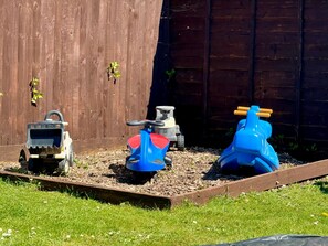 Three toy tractors in a garden bed with a wooden fence in the background. - The Pepper Pot - Niton, Isle of Wight (Niton)