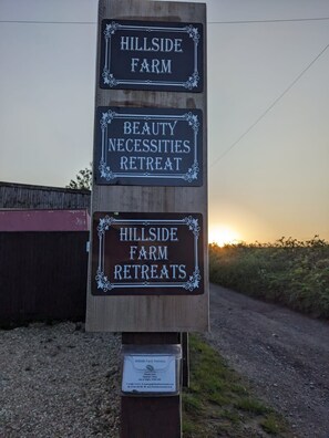 Un panneau indicateur avec trois panneaux publicitaires pour les séjours à la ferme Hillside, dont un séjour axé sur les soins de beauté.