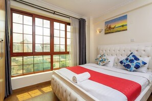 A hotel room with a large window, a bed with white bedding, and a painting on the wall. - Skyline View Palace Apartment (Nairobi)