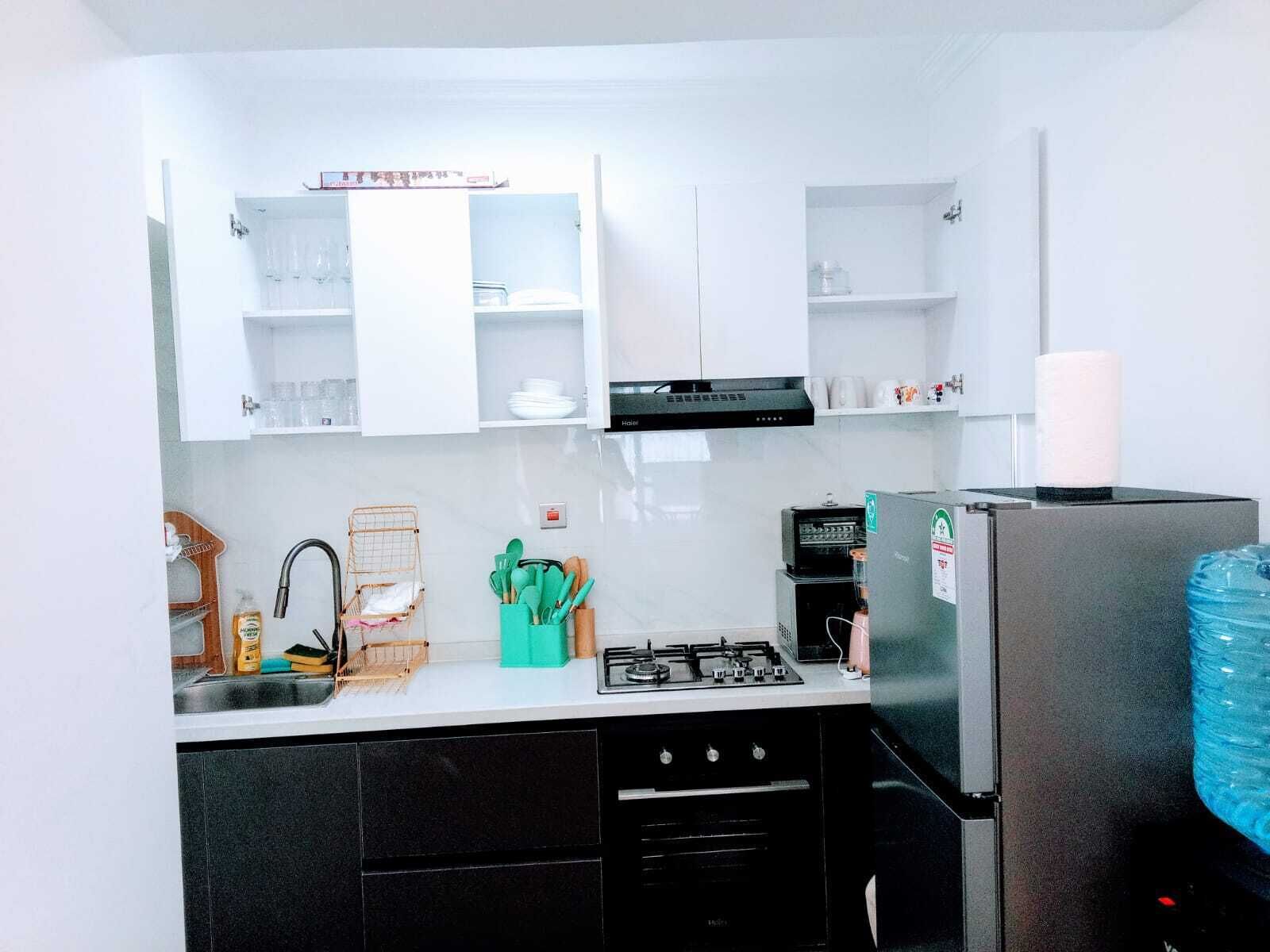 A compact kitchen with white cabinets, a gas stove, a black refrigerator, and a small sink.
