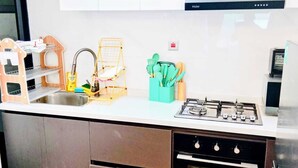A kitchen with a gas stove, a sink, a dish rack, and a spice rack. - Skyline View Palace Apartment (Nairobi)