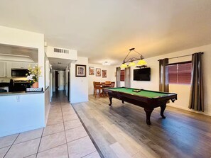 A spacious living area with a pool table, a kitchen with a welcome sign, and a dining area with a TV. - Your Tampa Bay Vacation Entertainment Home (Tampa)