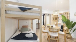A bunk bed with a notebook and a pillow, a dining table with chairs, and a potted plant. - Travel Habitat Loft Parque de Cabecera 2 (Valencia)