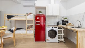 A compact room with a bunk bed, a red refrigerator, a washing machine, a microwave, and a sink. - Travel Habitat Loft Parque de Cabecera 2 (Valencia)
