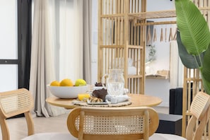 A dining area with a round table, chairs, a bowl of fruit, a pitcher, and a coffee pot. - Travel Habitat Loft Parque de Cabecera 2 (Valencia)