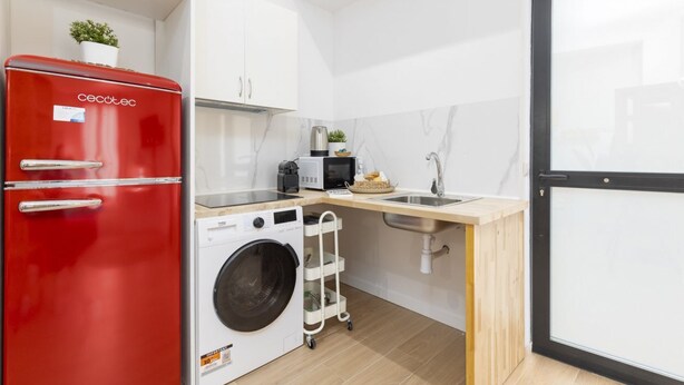 A compact kitchen with a red refrigerator, a washing machine, a microwave, and a sink. - Travel Habitat Loft Parque de Cabecera 2 (Valencia)