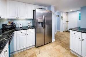 Eine Küche mit weißen Schränken, einem Edelstahl-Kühlschrank, einem Toaster und einer Kaffeemaschine.