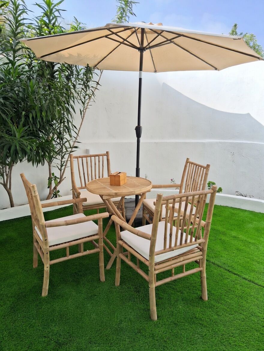 Une table ronde en bois, quatre chaises, un parasol et une petite boîte posée sur la table.