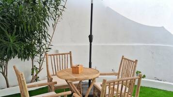 Une table ronde en bois, quatre chaises, un parasol et une petite boîte posée sur la table.