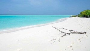 Uma praia com areia branca e água turquesa transparente.