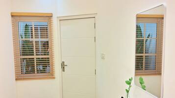 A room with a white desk, a laptop, a white chair, and a door with a window.