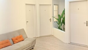 Um interior moderno com ventilador de teto, um sofá de cor clara com almofadas laranja e três portas fechadas.