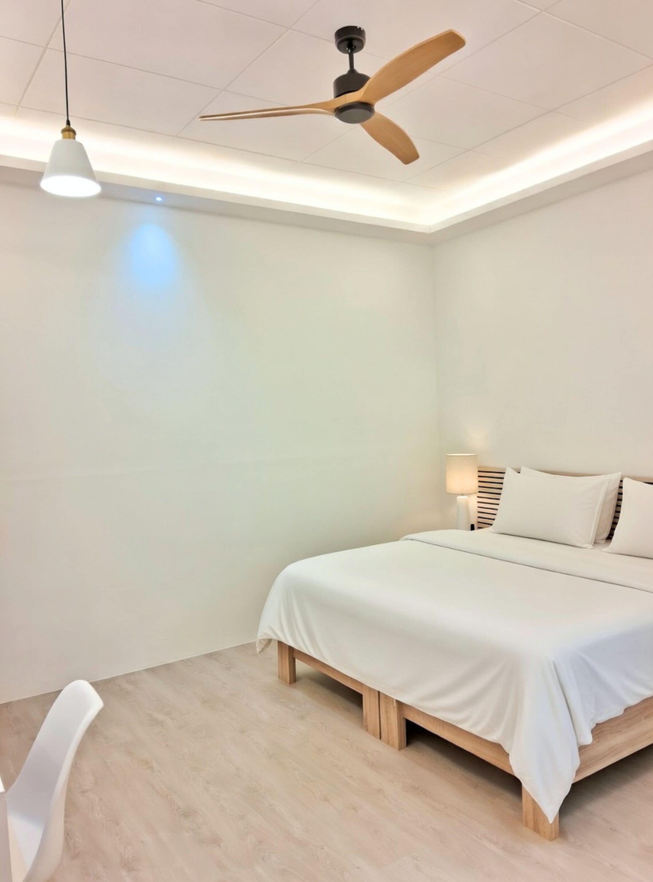 Une chambre à coucher avec un lit, un ventilateur de plafond, une lampe de chevet et une chaise.