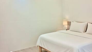 Une chambre à coucher avec un lit, un ventilateur de plafond, une lampe de chevet et une chaise.