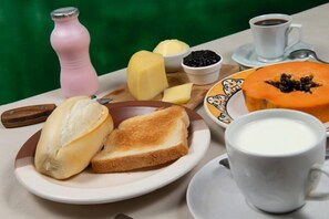 A breakfast tray with bread, butter, jam, a sliced fruit, a cup of coffee, and a milk jug. - Pousada E Apartamento Buda Buzios (Buzios)